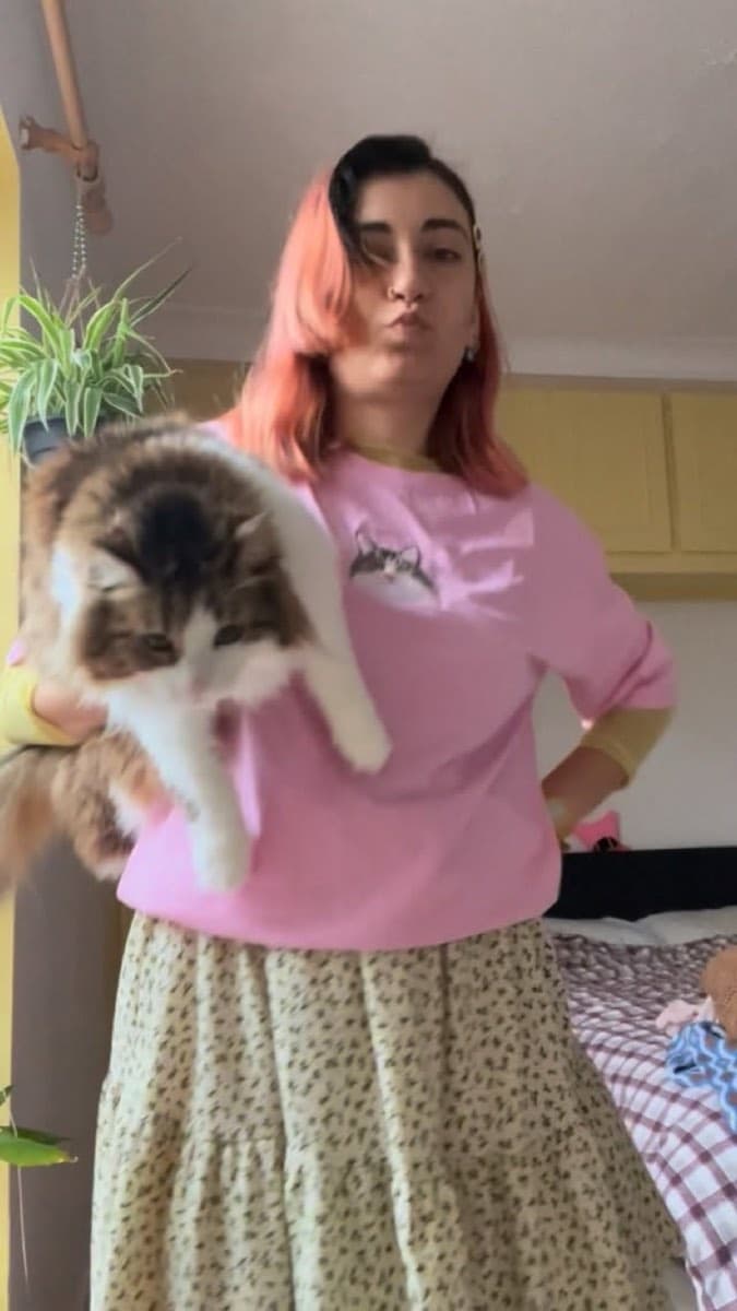 Müşteri, kedisiyle birlikte pembe nakışlı sweatshirt giyerken